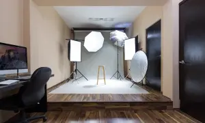 Gotowy pokój fotografa: lampy, statywy, taboret i komputer czekają na sesję.
