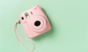 Różowy aparat Instax Mini 8 na pastelowym tle. Dowiedz się, jak działa Instax, tworząc natychmiastowe zdjęcia.