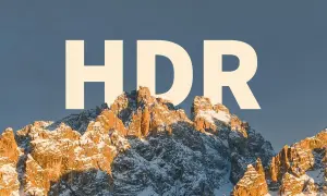 Zimowe szczyty górskie oświetlone słońcem, z napisem "HDR" na niebie.