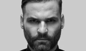 Intensywne spojrzenie Karola Grygoruka w czarno-białym kadrze. Mężczyzna z zarostem i zaczesanymi włosami patrzy prosto w obiektyw.