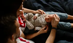 Ciepła sesja noworodkowa w domu. Rodzice czule trzymają swoje maleństwo, otulając je miłością.