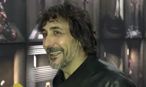 Uśmiechnięty mężczyzna z kręconymi włosami i brodą, w czarnej kurtce. To Eugenio Recuenco, artysta znany z niezwykłych wizualizacji.