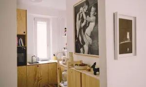 Wnętrze z drewnianymi meblami, czarno-białym zdjęciem autorstwa Bartka Wieczorka i małą figurką czarnego zwierzęcia.