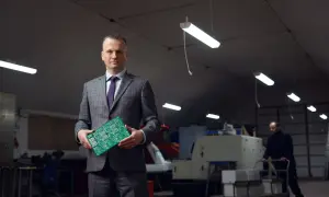 Portret mężczyzny w garniturze trzymającego płytkę drukowaną. Wizerunek inaczej ukazuje jego rolę w branży technologicznej.