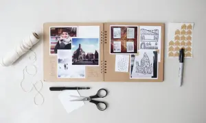 Kreatywne projekty fotograficzne w albumie: zdjęcia, szkice budynków, notatki i akcesoria do tworzenia.