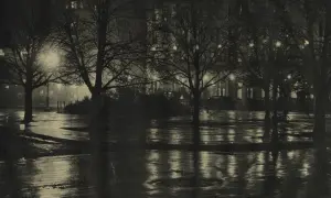 Nocny park po deszczu, drzewa bez liści, mokre ścieżki odbijające światła budynków. Alfred Stieglitz uchwycił atmosferę miasta.