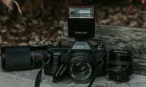 Stary aparat Canon 750 z lampą błyskową Canon Speedlite 244T i obiektywami. Lampa błyskowa inaczej niż współczesne, to retro sprzęt.