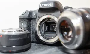 Aparat Canon z odłączonym obiektywem i dwoma innymi akcesoriami, które mogą wpływać na ekwiwalent ogniskowej.