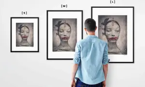 Mężczyzna ogląda trzy obrazy Ewy Ćwikły. Na każdym z nich widnieje surrealistyczny portret kobiety z motylami i czerwonymi ustami.
