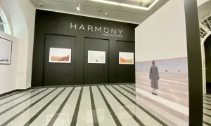 Wystawa "HARMONY" Marcina Ryczka. W galerii widzimy fotografie mnichów i dużą instalację z podobizną postaci w szarym płaszczu.
