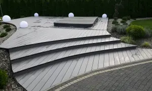 Nowoczesny taras z szarej deski kompozytowej, z jacuzzi i kulistymi lampami. Solidny **alu bond** stanowi bazę dla tej eleganckiej konstrukcji.