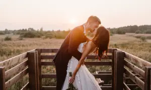 Para młoda podczas sesji w plenerze, całująca się na tle zachodzącego słońca.