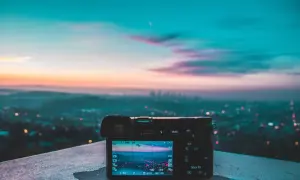 Aparat fotograficzny na tle miasta o zachodzie słońca. Piękne, pastelowe światło zastane maluje niebo, tworząc magiczną atmosferę.