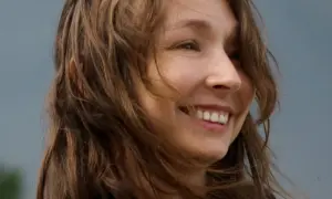 Uśmiechnięta Karolina Jonderko z rozwianymi włosami na tle nieba.