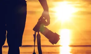 Sylwetka osoby z aparatem, gotowa do uchwycenia piękna, jak fotografować zachód słońca nad morzem.