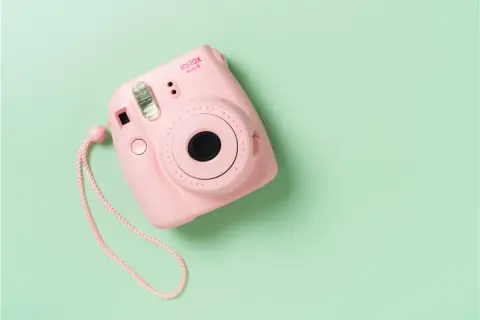 Różowy aparat Instax Mini 8 na pastelowym tle. Dowiedz się, jak działa Instax, tworząc natychmiastowe zdjęcia.