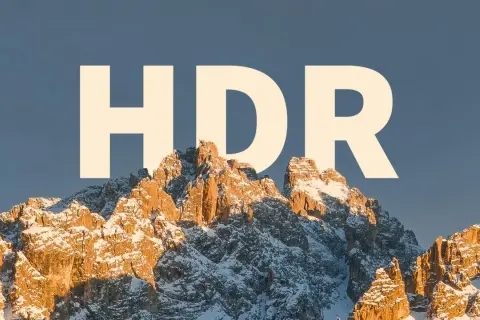 Zimowe szczyty górskie oświetlone słońcem, z napisem "HDR" na niebie.