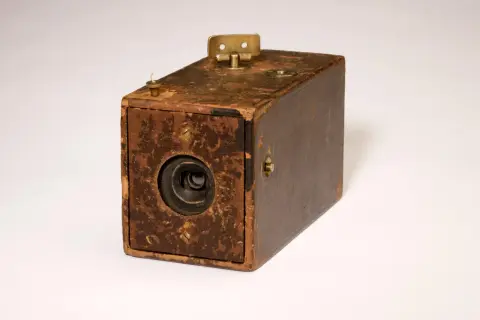 Zniszczona, brązowa skrzynka aparatu fotograficznego, podobna do tych, które stworzył założyciel firmy Kodak.