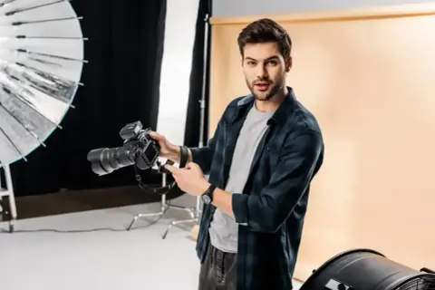 Świetny fotograf z aparatem w studiu. Widać jego pasję i talent.