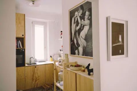 Wnętrze z drewnianymi meblami, czarno-białym zdjęciem autorstwa Bartka Wieczorka i małą figurką czarnego zwierzęcia.