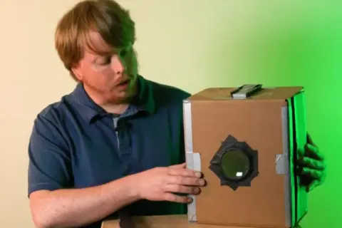 Mężczyzna pokazuje, jak zrobić camera obscura z kartonu.