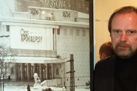 Chris Niedenthal obok plakatu filmu "Czas Apokalipsy" z kinem Moskwa w tle.