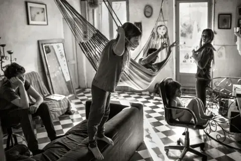 Dzieci bawią się w hamakach, jak na zdjęciach Alain Laboile. Jedno stoi na kanapie, inne w fotelu.