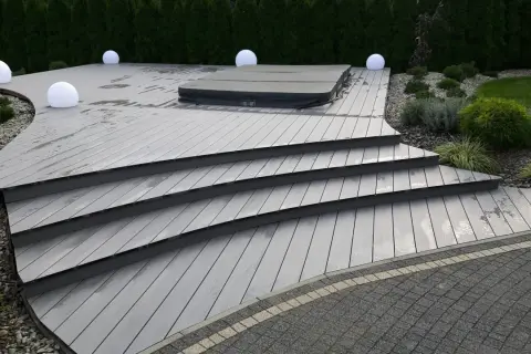 Nowoczesny taras z szarej deski kompozytowej, z jacuzzi i kulistymi lampami. Solidny **alu bond** stanowi bazę dla tej eleganckiej konstrukcji.