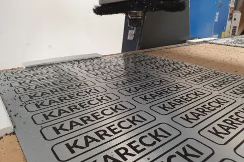 Cięcie CNC na płycie alu dibond z powtarzającym się napisem KARECKI.