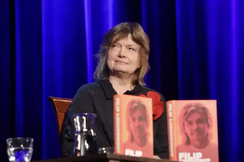 Maja Łobodzińska siedzi obok dwóch książek z wizerunkiem Filipa.