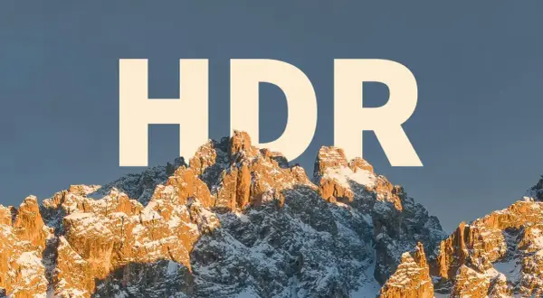 Zimowe szczyty górskie oświetlone słońcem, z napisem "HDR" na niebie.