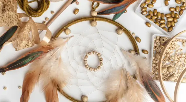Łapacze snów, pióra, koraliki i koronki tworzą inspirującą sesję boho.