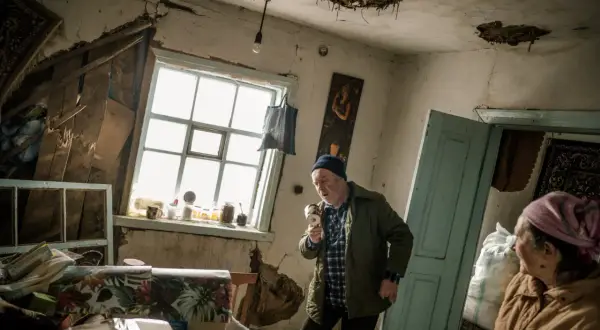 Wojciech Grzedzinski uchwycił moment, gdy mężczyzna w zniszczonym pokoju trzyma kubek jak mikrofon.