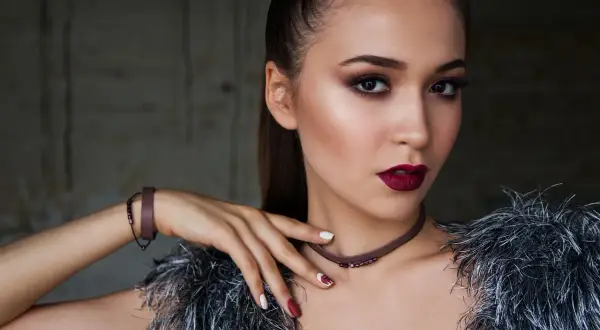 Elegancki makijaż dla brązowych oczu i ciemnych włosów. Ciemne usta i smoky eyes podkreślają urodę modelki.