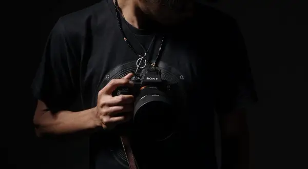 Mężczyzna w czarnej koszulce trzyma aparat Sony. Może to być jego zgłoszenie do konkursu fotograficznego.