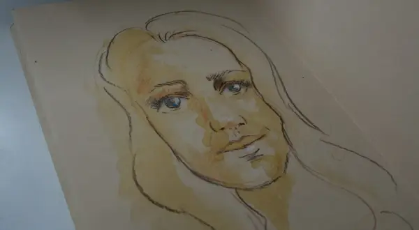 Szkic twarzy kobiety z niebieskimi oczami, wykonany kredkami. To co to jest autoportret, pokazuje artystyczną wizję.