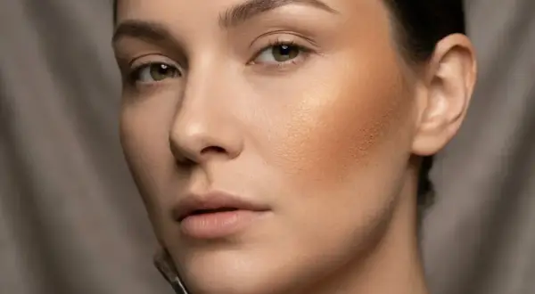Kobieta z pędzlem do makijażu aplikuje bronzer, tworząc ciepły, promienny wygląd.