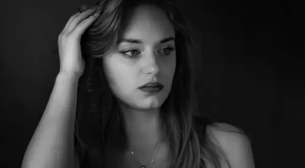 Kobieta z dłonią we włosach, w nastrojowym, low key fotografii.