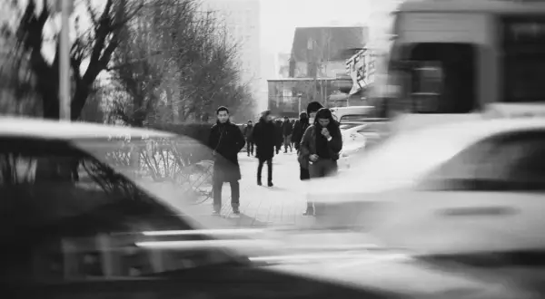 Zdjecia z analoga. Ludzie idący ulicą, rozmyte samochody i drzewa tworzą dynamiczną scenę miejską.