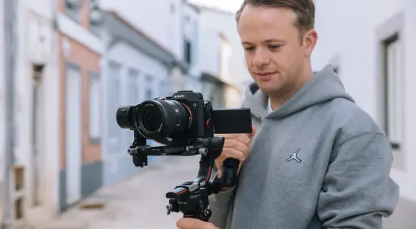 Mężczyzna trzyma stabilizator z korpusem aparatu fotograficznego Sony Alpha 7.