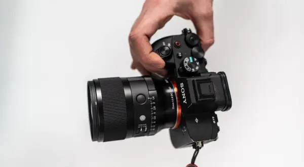 Dłoń trzyma aparat Sony z obiektywem 35 mm f/1.4. Idealny do portretów i krajobrazów, ten obiektyw 35 mm do czego służy?