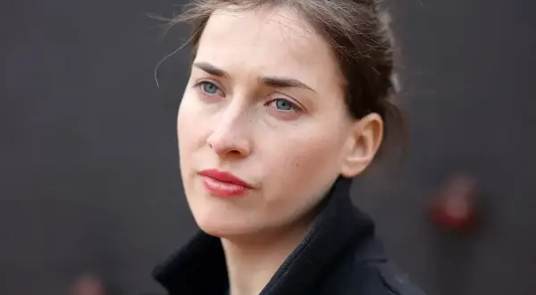Portret kobiety w czarnym płaszczu, z niebieskimi oczami i rozpuszczonymi włosami. Plan średni.