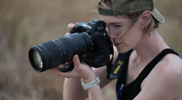 Kobieta w czapce z daszkiem celuje obiektywem aparatu Nikon Z, gotowa uchwycić chwilę. Czy to jej rywal Nikon?