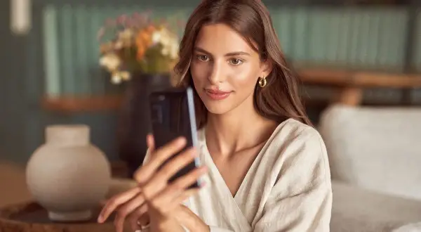 Kobieta robi selfie w lustrze, ale jej twarz jest zasłonięta przez telefon.