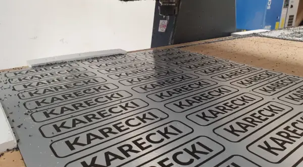 Cięcie CNC na płycie alu dibond z powtarzającym się napisem KARECKI.