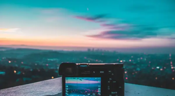 Aparat fotograficzny na tle miasta o zachodzie słońca. Piękne, pastelowe światło zastane maluje niebo, tworząc magiczną atmosferę.