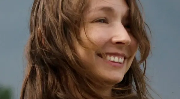Uśmiechnięta Karolina Jonderko z rozwianymi włosami na tle nieba.