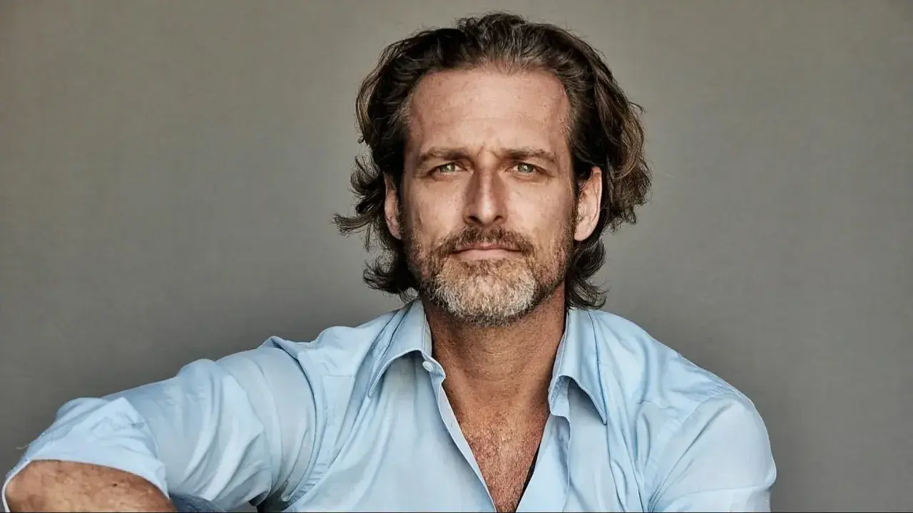 Portret mężczyzny o zielonych oczach i krótko przystrzyżonej brodzie, ubranego w błękitną koszulę. To Alexi Lubomirski.