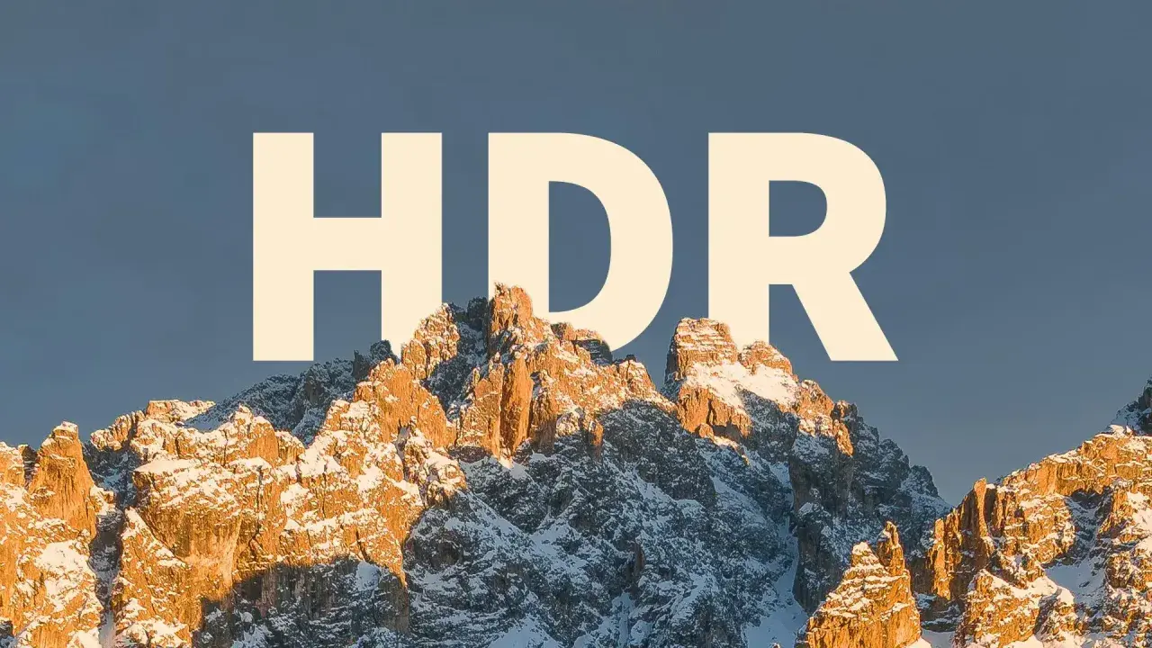 Zimowe szczyty górskie oświetlone słońcem, z napisem "HDR" na niebie.