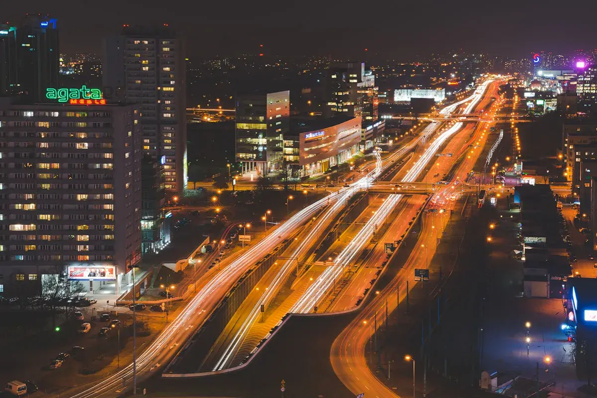 Rozświetlone autostrady i budynki tworzą dynamiczny obraz miasta nocą.